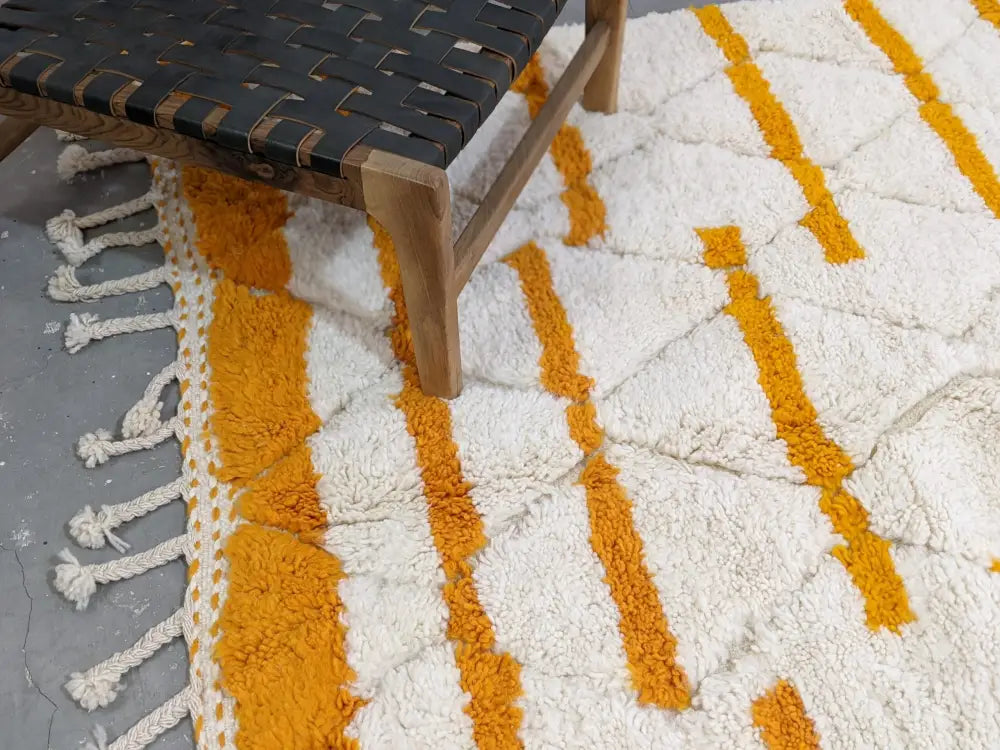 A plush white and mustard-yellow geometric beni ouarain rug with fringed edges moroccan handmade decorbites