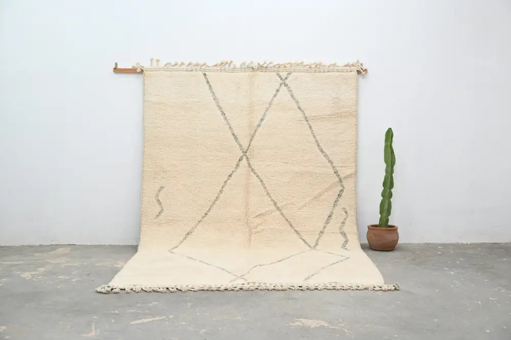 Beige moroccan handmade beni ouarain rug with geometric black lines and fringed edges measuring 303 x 212 cm
