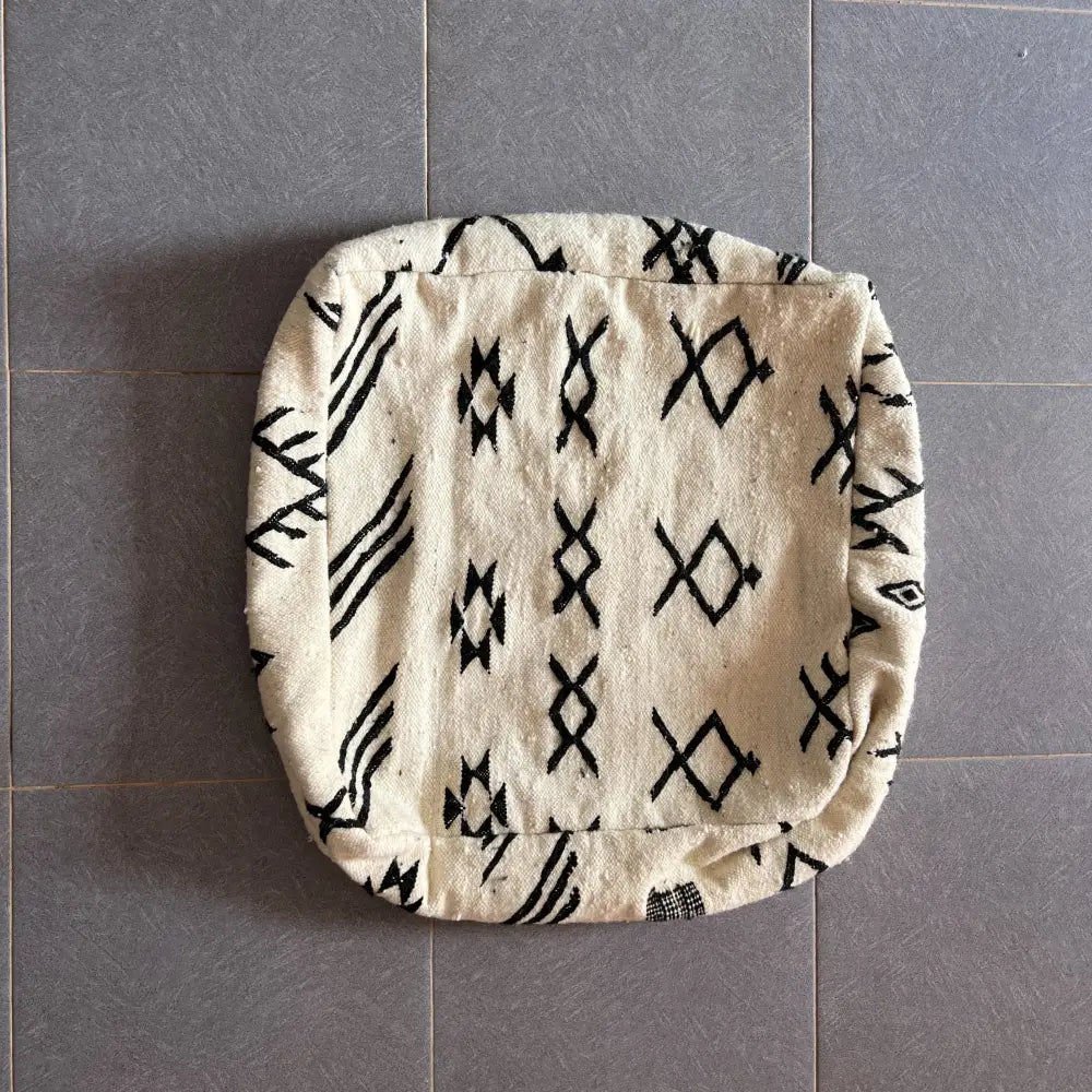 Cream-colored decorbites moroccan handmade pouf 60cm x 60cm with black geometric woven textile design
