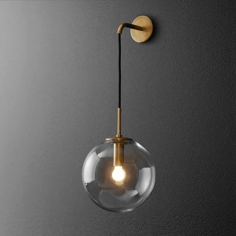 DecorBites™ Moroccan modern wall sconce with sleek brass finish and clear glass globe illuminated by black cord suspension