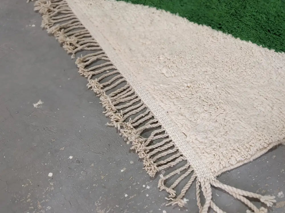 Cream-colored traditional azilal rug with textured wool, fringed edge, and green border by DecorBites™ 298x220cm