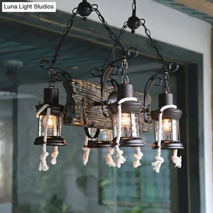 Black wrought iron island lamp with three lantern-style lights, glass enclosures, white hemp rope tassels, and bulb base design