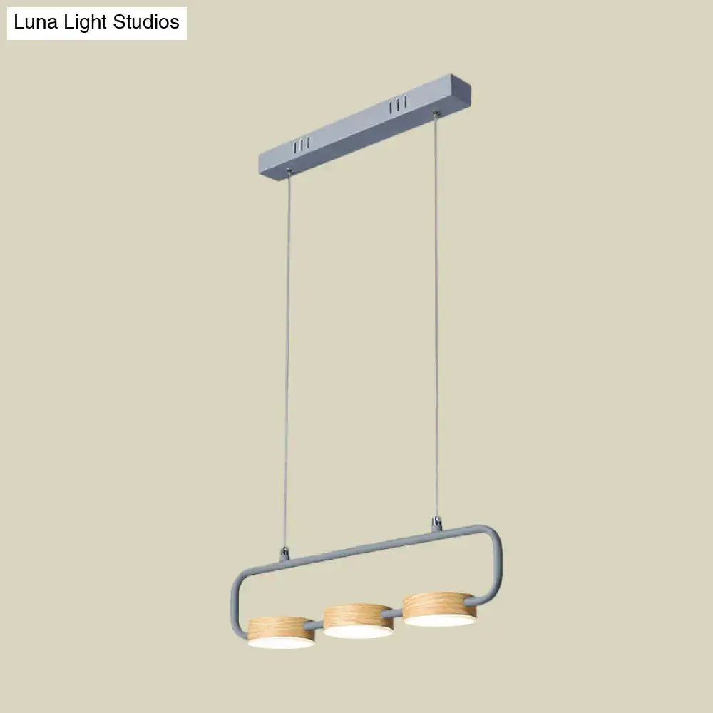 Modern minimalist hanging pendant with gray metal frame and wooden shades providing warm light for kitchen island