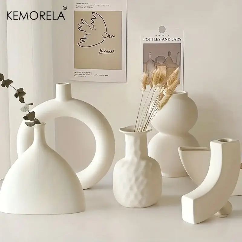 A set of minimalist white nordic ceramic vases including a ring-shaped ceramic vase holding eucalyptus leaves by decorbites