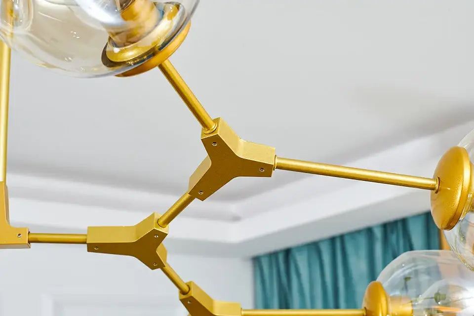 Gold-toned metal nordic chandelier with clear glass globe shades for modern living rooms and dining spaces