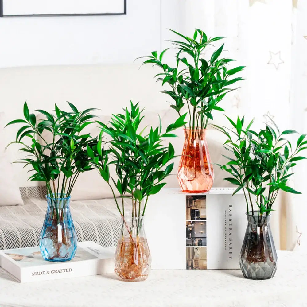 Three faceted glass vases in blue amber and gray holding green plants perfect as nordic flower vases for modern home decor