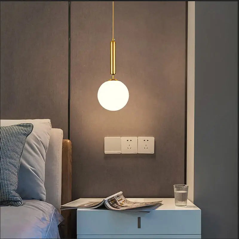 Gold-toned pendant light with a spherical glass ball globe as the modern light source by DecorBites Nordic