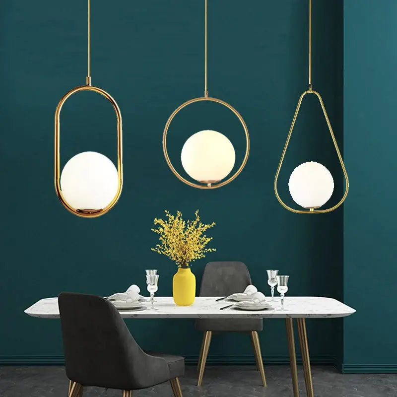Three decorbites™ nordic glass ball pendant lights with gold-toned metal frames and frosted glass shades above table