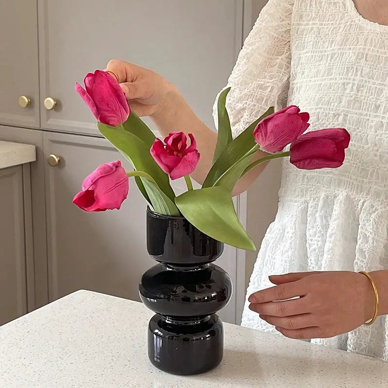DecorBites™ nordic glass vase home decor featuring a black glossy stacked design holding vibrant pink tulips