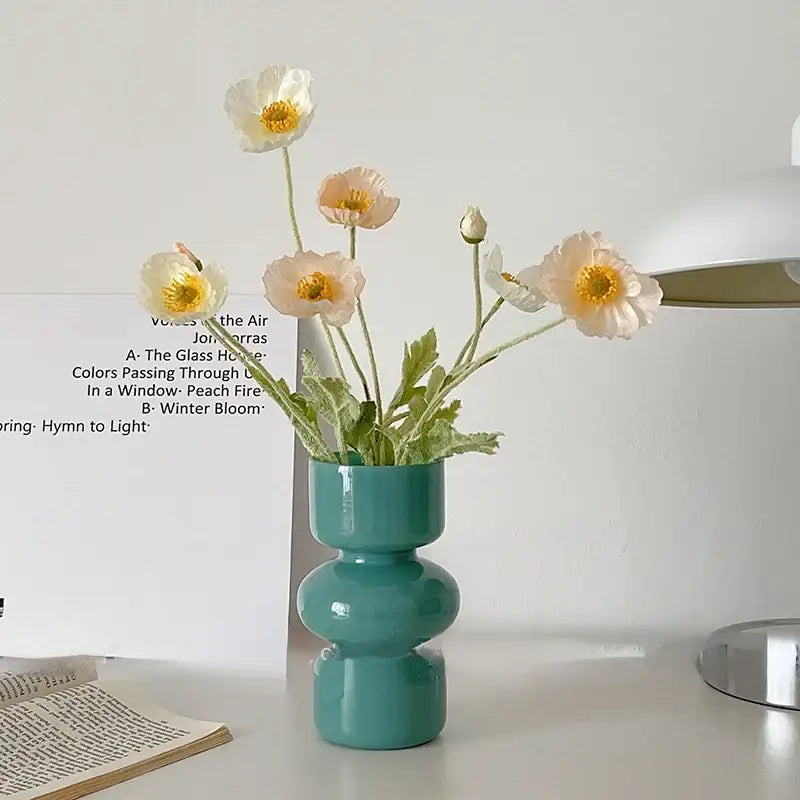 A sleek teal ceramic vase with a modern stacked design holds white and peach poppies for vase home decor