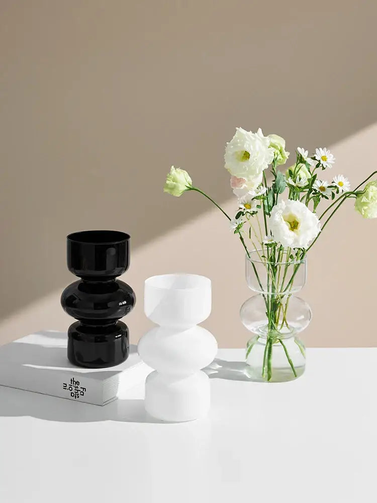 DecorBites™ nordic glass vase home decor with a sleek geometric design holding white and green flowers