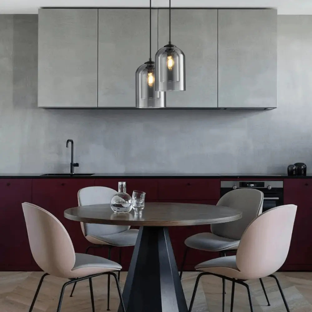 Modern nordic glass pendant lighting by decorbites features clear glass shades with warm filament bulbs over a table