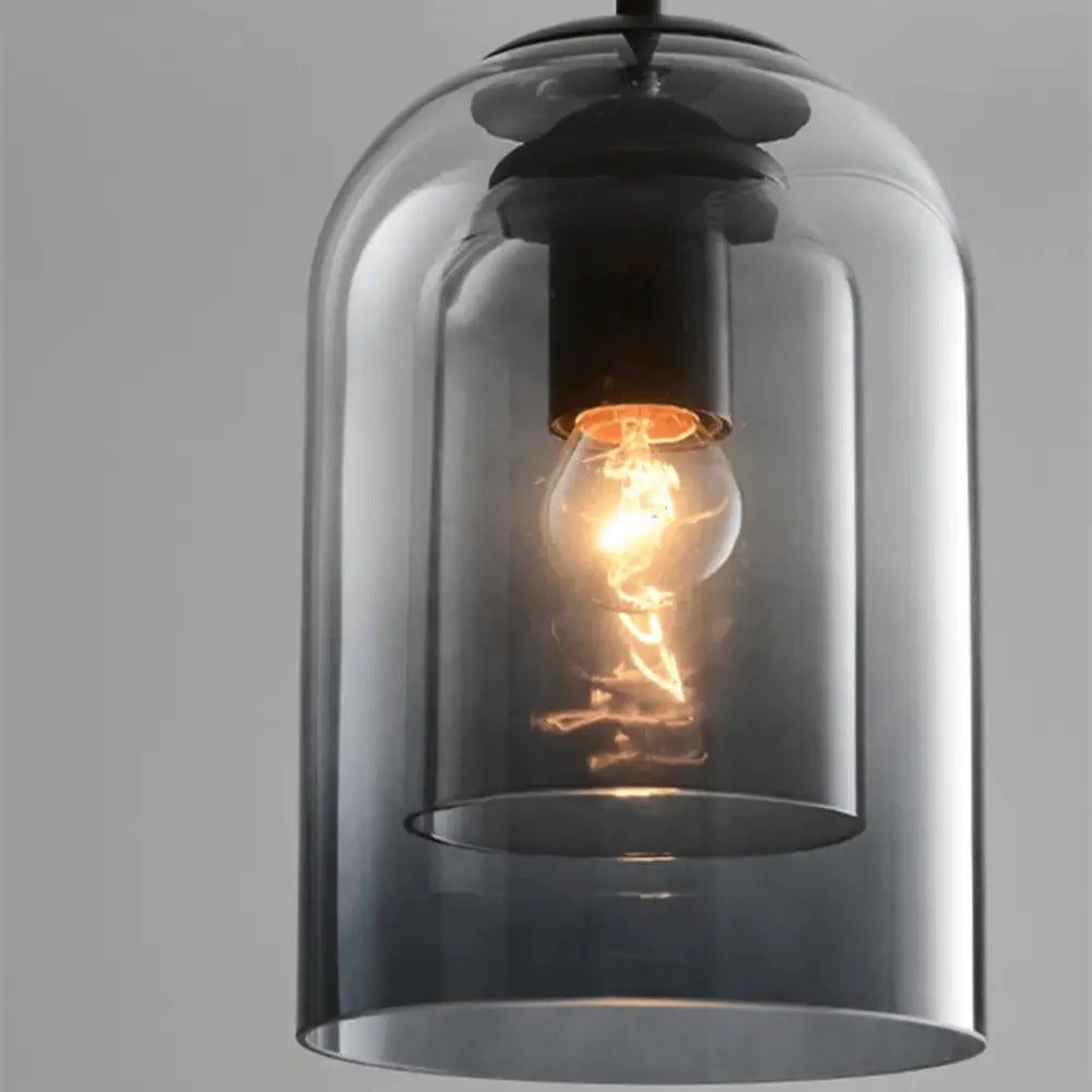 A decorbites™ nordic glass pendant lighting with a sleek smoked glass bell-shaped shade and warm filament bulb