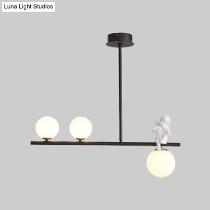 Black DecorBites™ Nordic island pendant light with three frosted opaline glass shades and white angel figurine detail