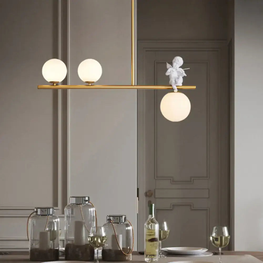 DecorBites Nordic Island angel pendant light in gold with three opaline glass shade bulbs and a white cherub figurine