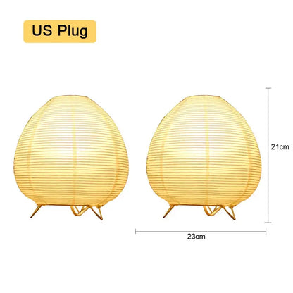 Two warm yellow paper lantern led table lamps with gold metal stands measuring 21cm tall and 23cm wide for home decor