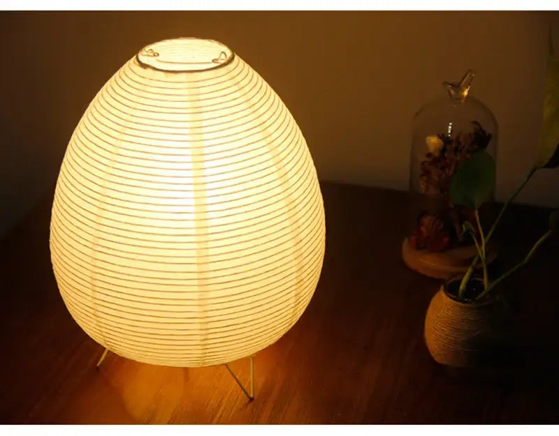 Warmly glowing egg-shaped led table lamp with metallic rim and slender wire legs for bedside or study lighting