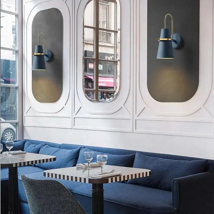 Navy blue upholstered booth with striped table tops and black legs near a DecorBites™ minimalist wall lamp
