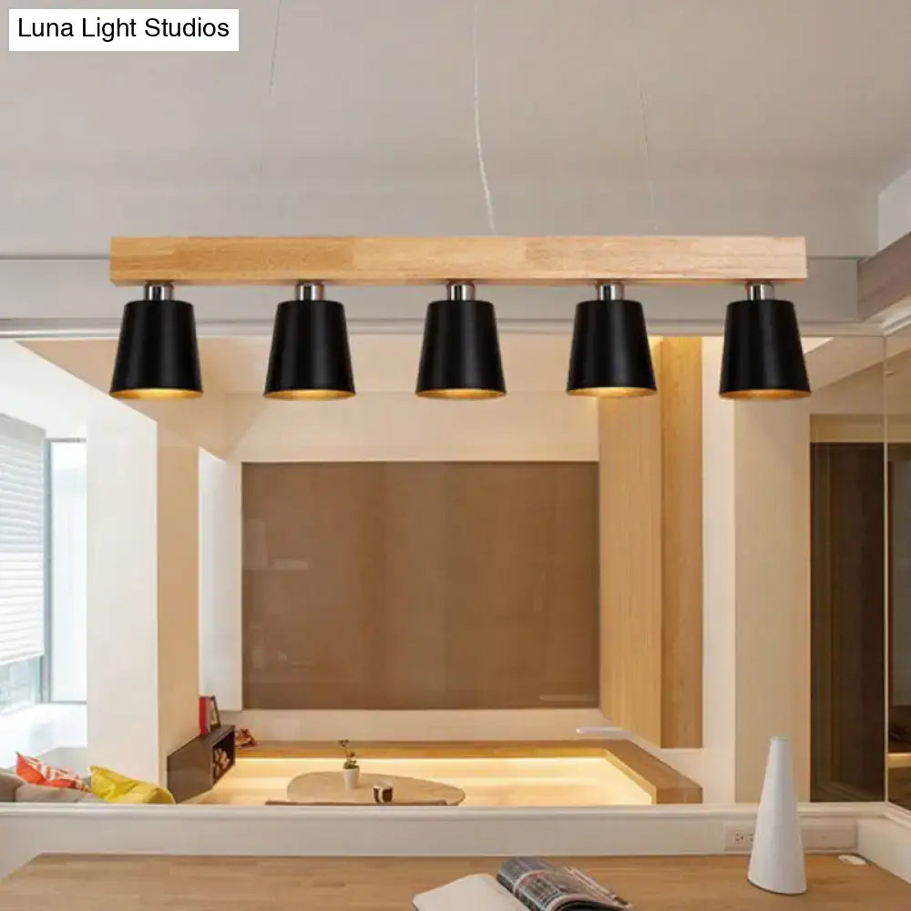 Modern black conical pendant lights with gold metal lampshade interiors mounted on a light wood beam for work rooms