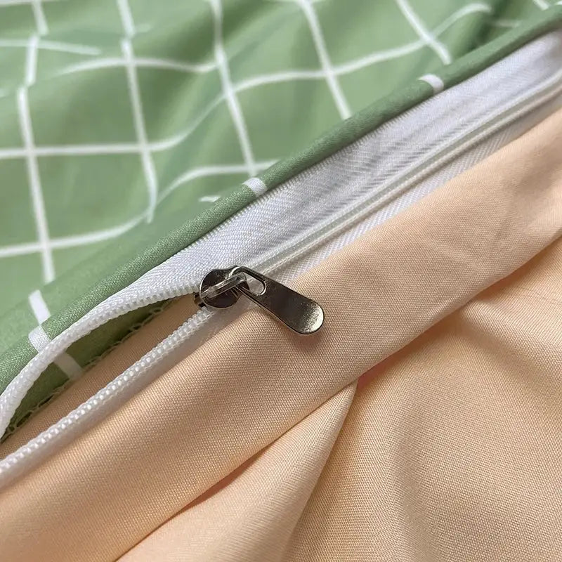 A silver-toned zipper with a metallic pull tab on a light green nordic plaid cotton bedding set from decorbites