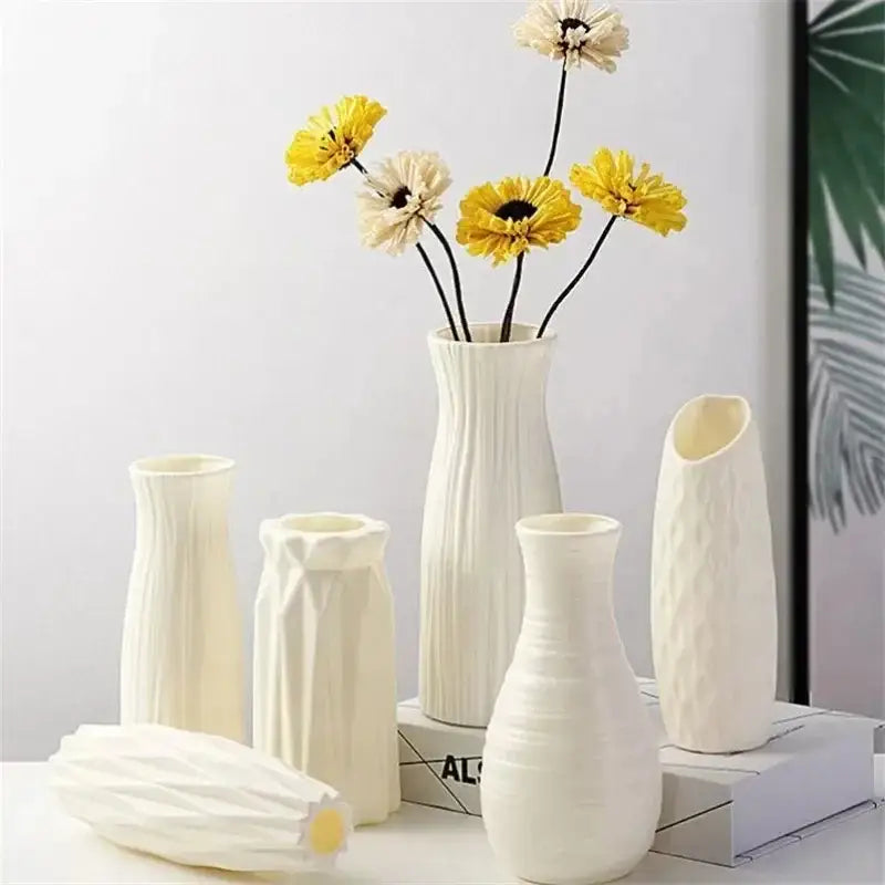 A collection of white nordic plastic vases with geometric textures arranged with dried yellow and cream flowers for modern decor
