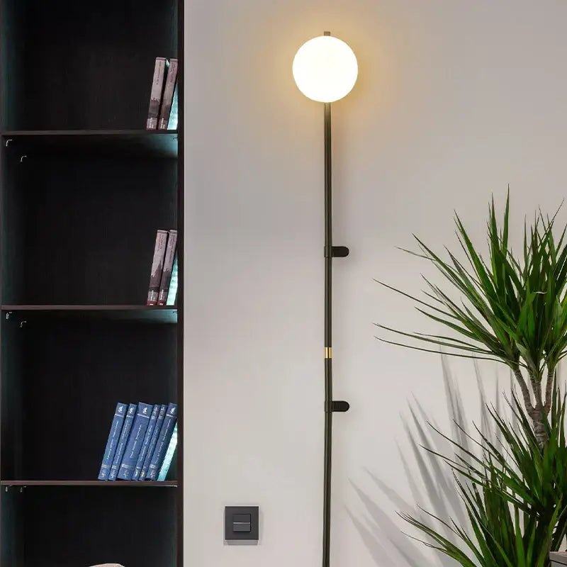 A sleek black DecorBites™ Nordic plug in wall lamp sconce with a glowing white spherical bulb
