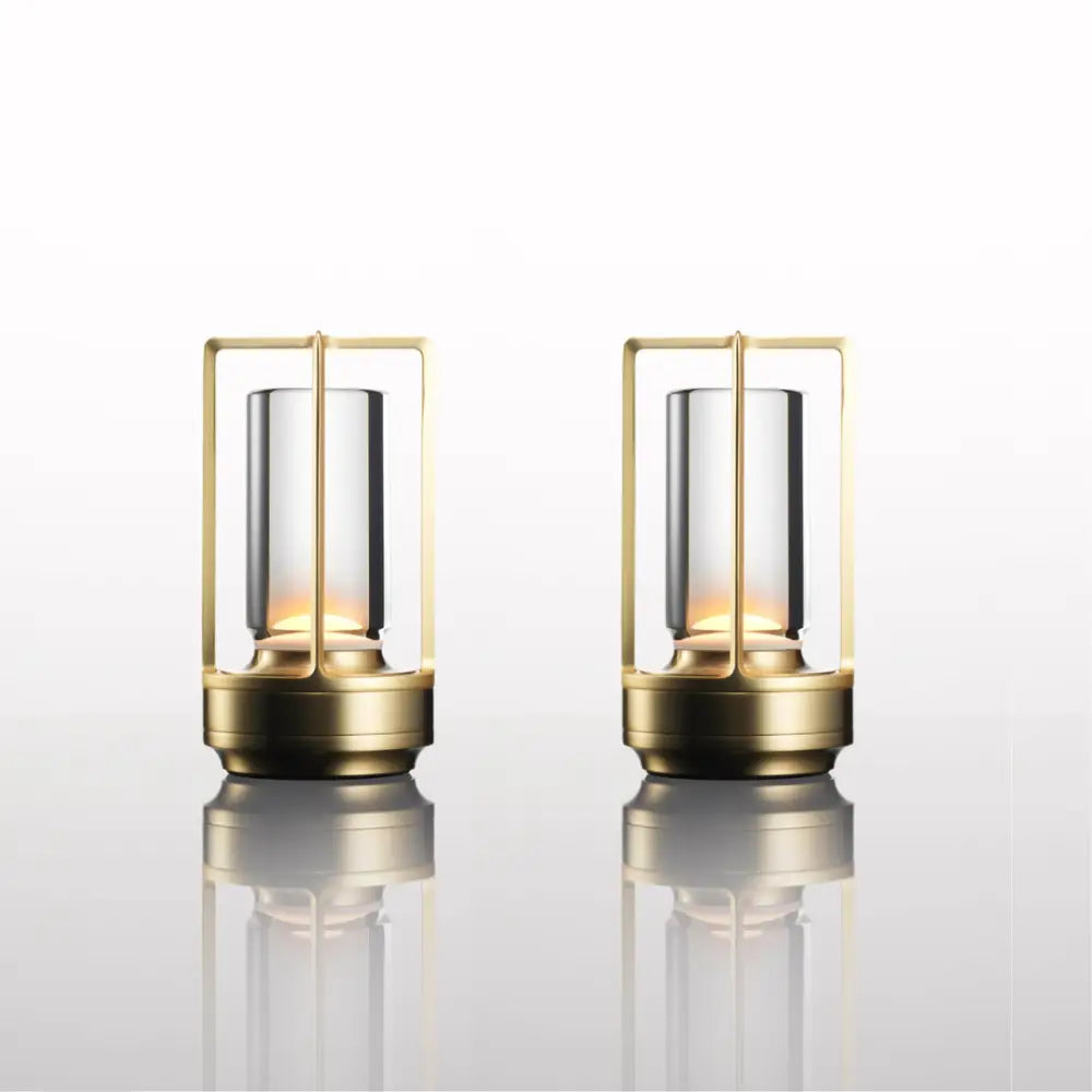 Two elegant brass-framed lanterns with clear glass cylinders and warm lighting in decorbites™ nordic rechargeable table lamp design