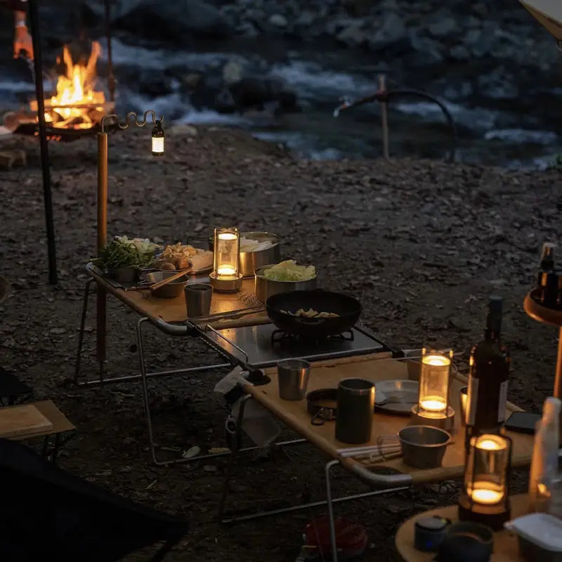 Warm-toned glass decorbites™ nordic rechargeable table lamp with glowing candles casting soft light over campsite