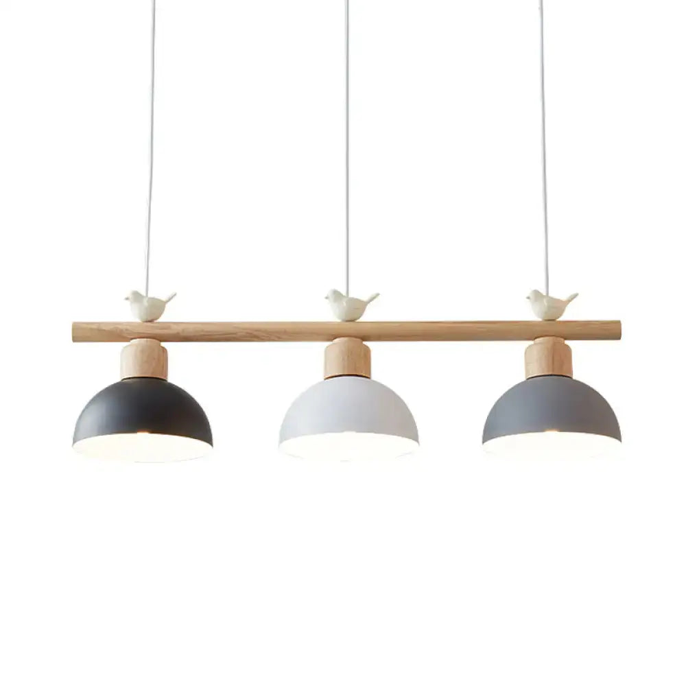 Modern three-light hanging island light with natural wood bar matte black white gray dome shades and bird decor