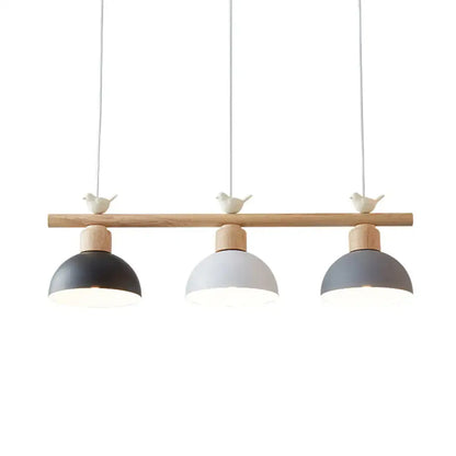 Modern three-light hanging island light with natural wood bar matte black white gray dome shades and bird decor