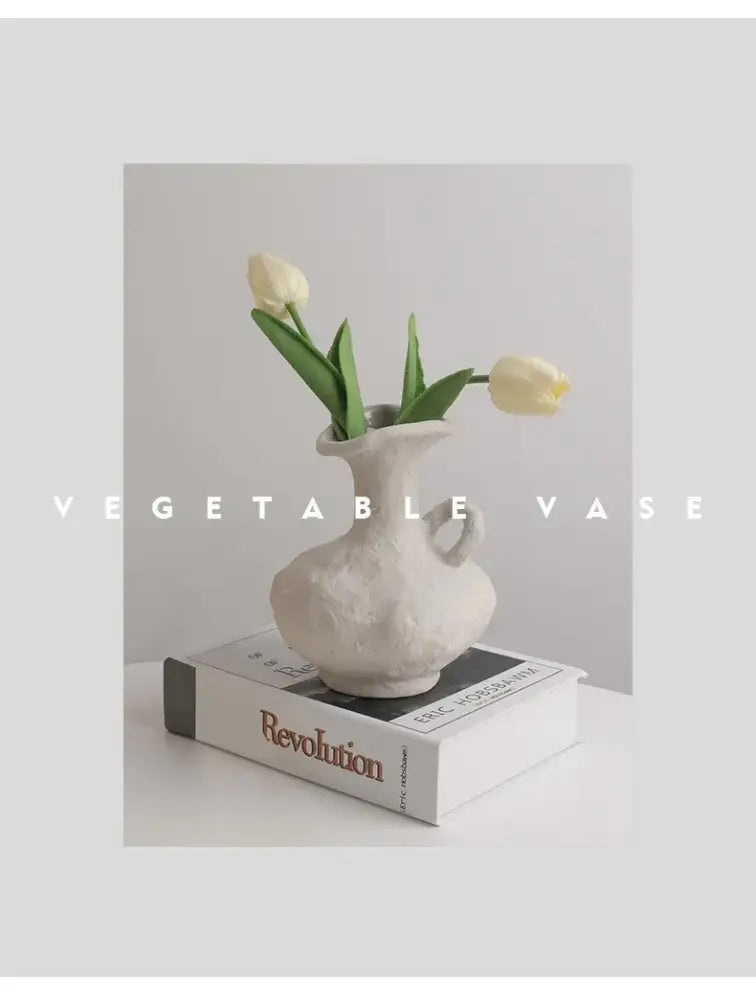 A textured white nordic style ceramic flower pot with handle holding two pale yellow tulips by decorbites