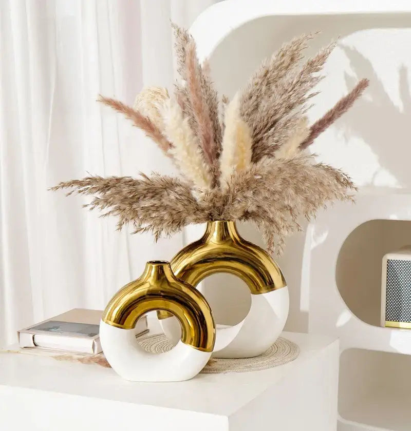 Two modern ceramic nordic style circle vases in glossy gold and white with distinctive curved ring design for flower arrangement