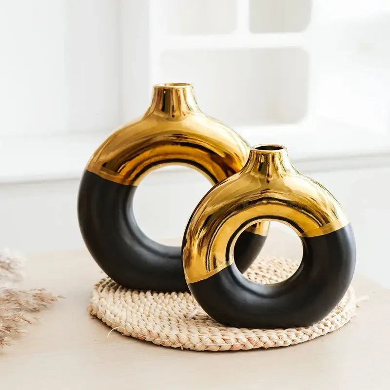 Two glossy ceramic nordic style circle vases in black and gold with modern circular design for flower arrangement