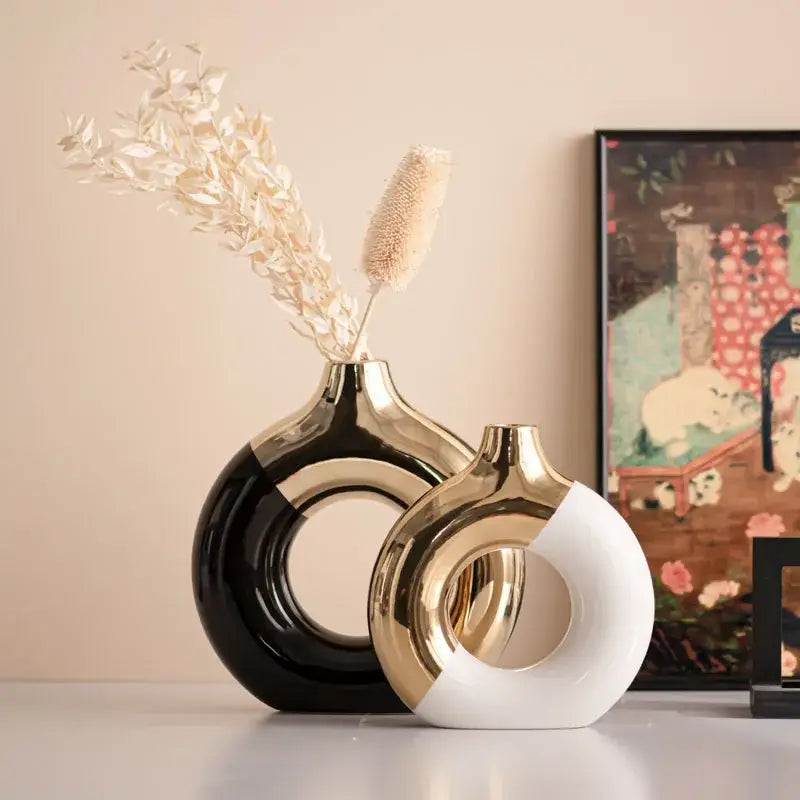 Two modern ceramic nordic style circle vases in glossy black and white with gold accents and distinctive cutout design