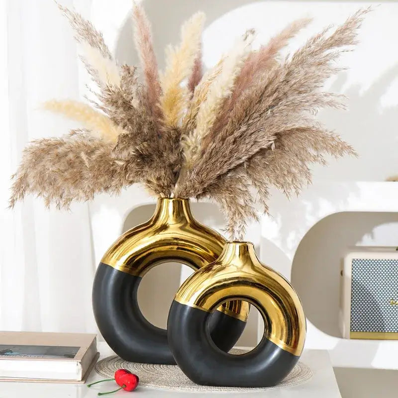 Two modern nordic style circle vases with a glossy black and gold metallic finish featuring an abstract ring design