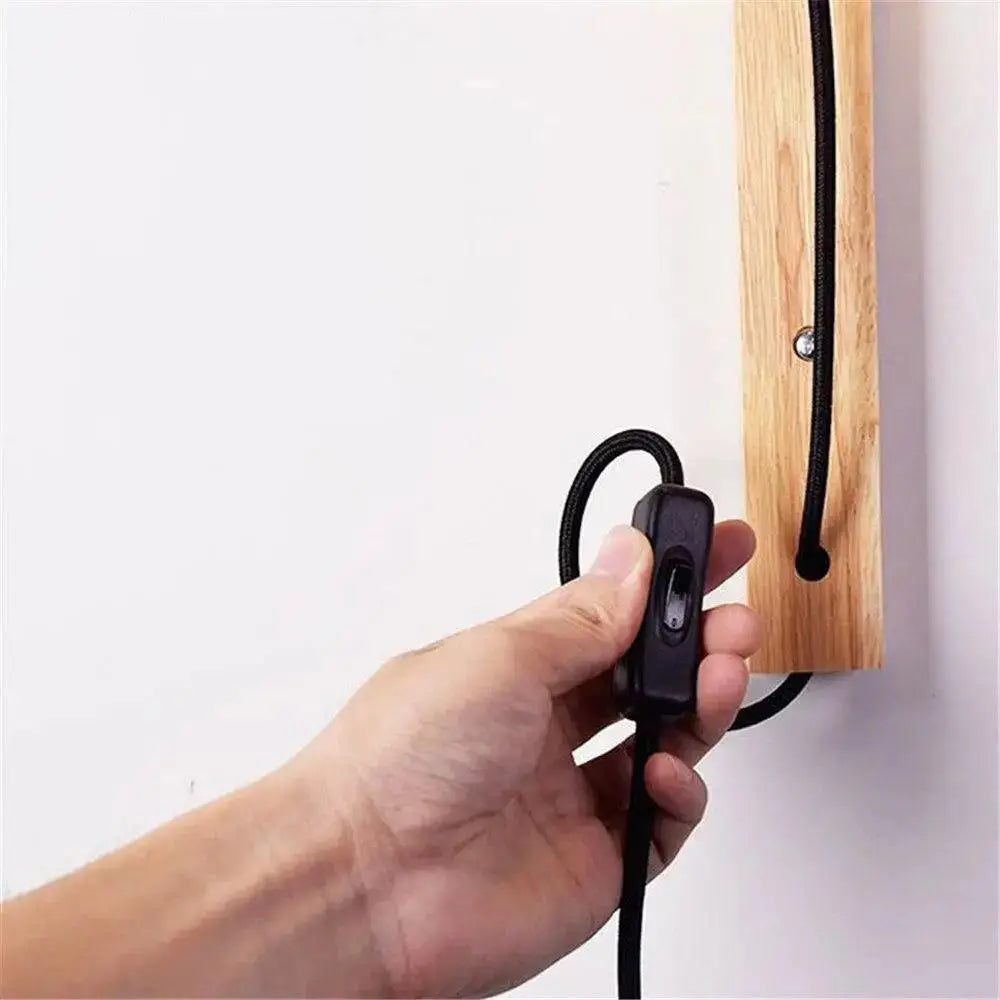 Black fabric-covered toggle switch on the DecorBites™ Nordic wood plug in wall sconce for mida wall use