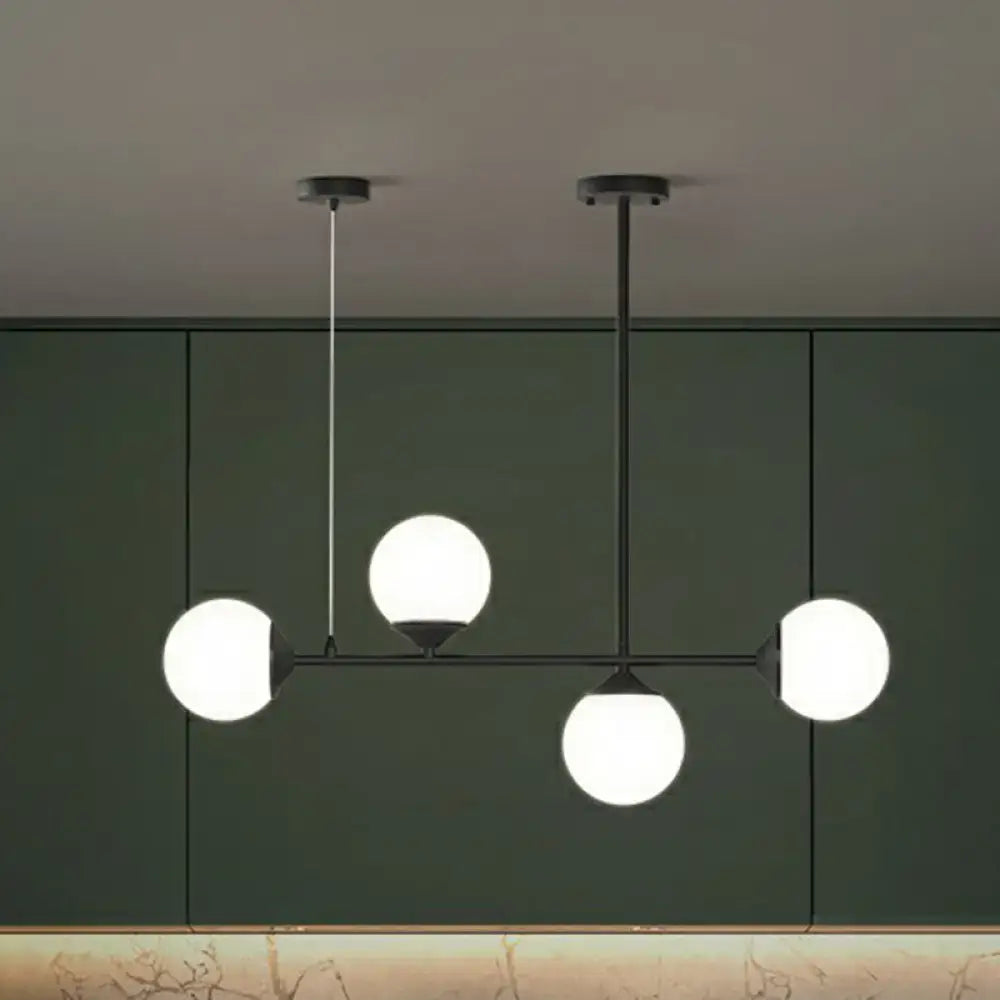 Modern black metal chandelier with four glowing white opaline glass globes for minimalist dining room island lighting