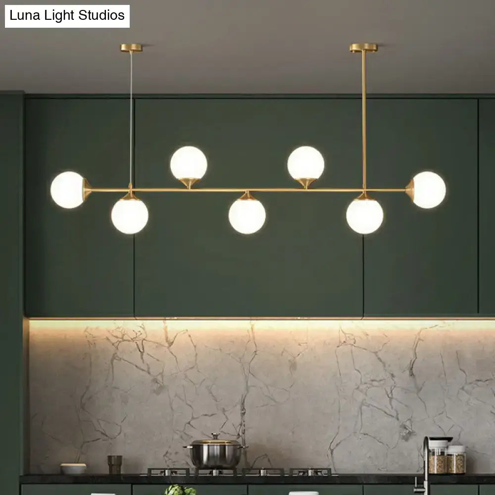 Modern brass pendant light with six white opaline glass globes for minimalist dining room island lighting
