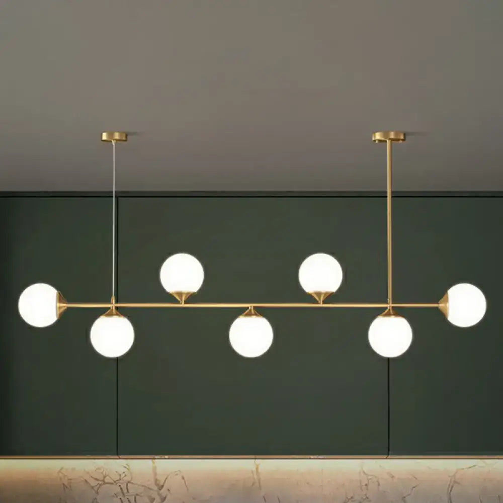 Modern gold-toned pendant light with five white opaline glass bulbs for minimalist dining room island lighting