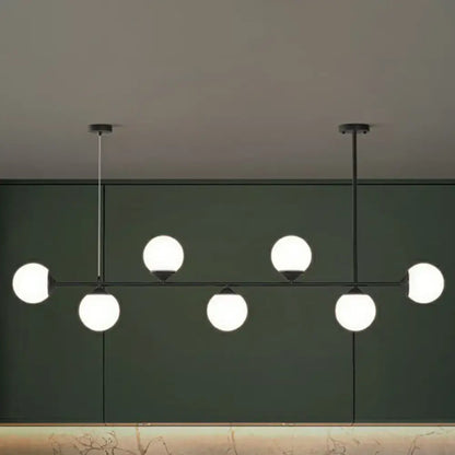 Modern black metal chandelier with six glowing white opaline glass bulbs for minimalist dining room island lighting