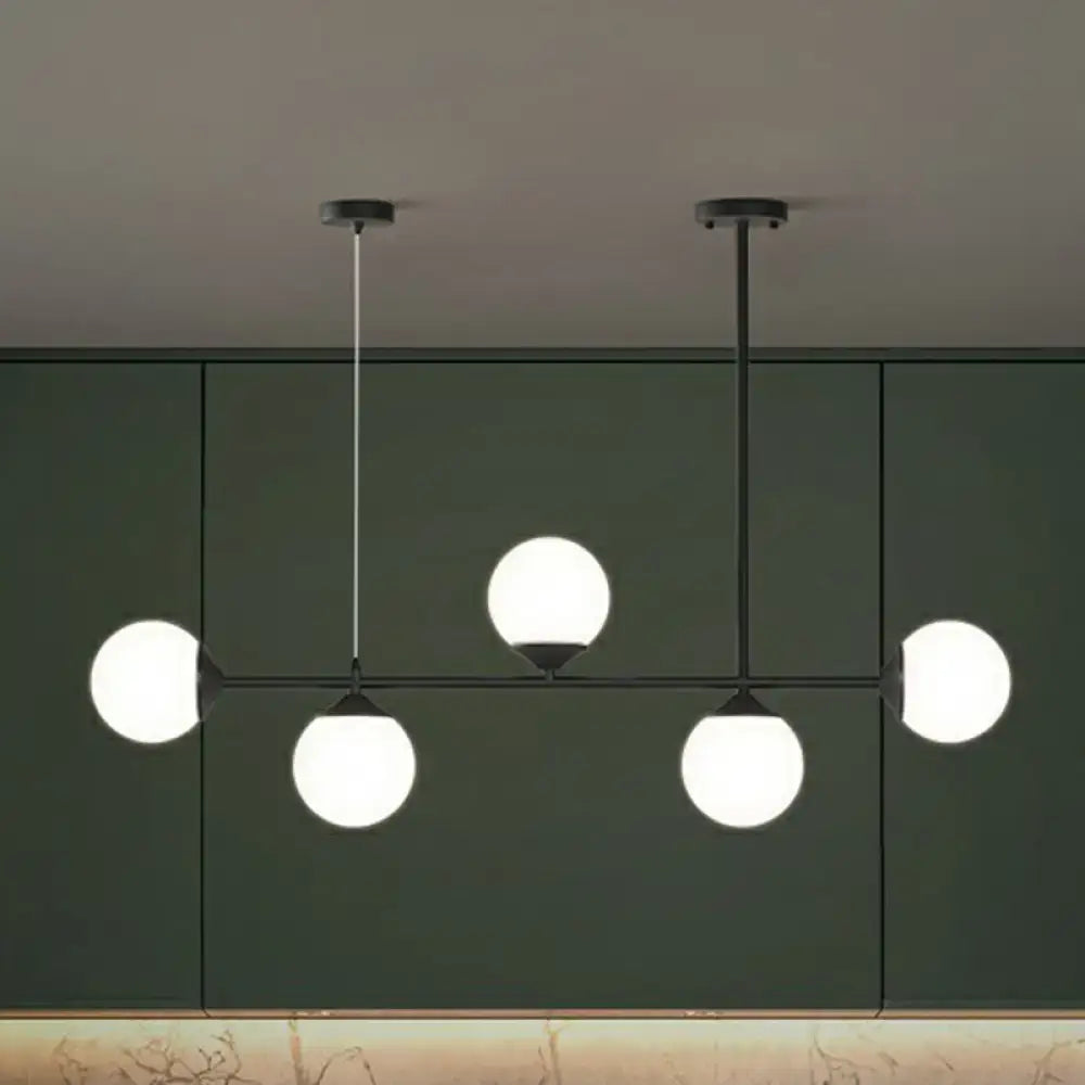 Modern black metal chandelier with five frosted glass globes for minimalist dining room island lighting