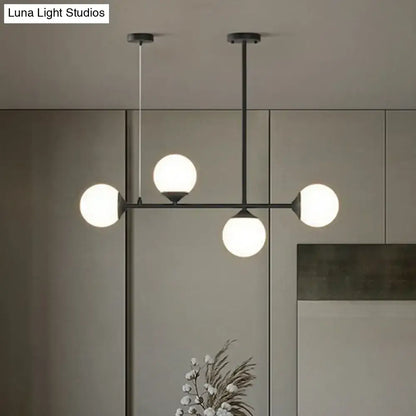 Modern black metal DecorBites pendant light with four frosted opaline glass globes for minimalist dining room island