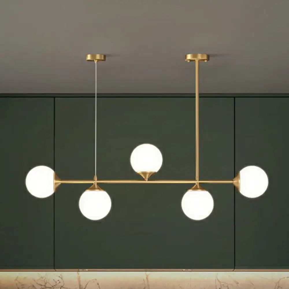 Modern brass pendant light with four frosted opaline glass globes for minimalist dining room island lighting
