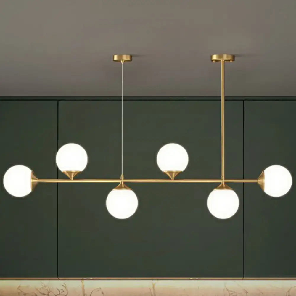 Modern brass pendant light with five frosted opaline glass globes for minimalist dining room island lighting
