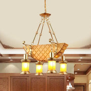 Gold-toned DecorBites pendant light with woven body, orange glass lanterns, and fish guitar design in warm yellow hue