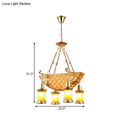 Gold-toned pendant light with woven basket frame and four lanterns featuring fish guitar design and orange glass accents