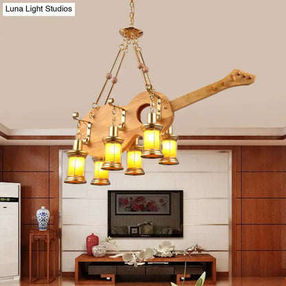 DecorBites™ pendant light in rustic wood with fish guitar design, brass accents, and warm orange glass shades