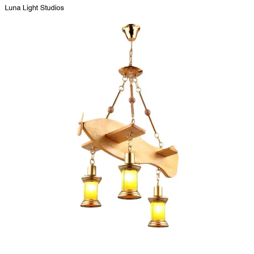 A brass and wood airplane-shaped pendant light with glowing orange glass lanterns featuring fish guitar design