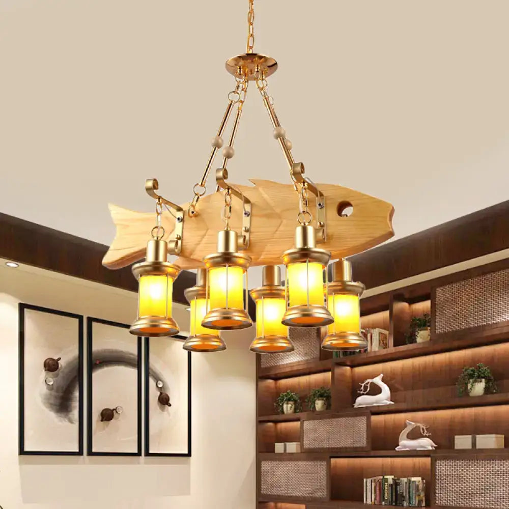 Golden fish-shaped wooden pendant light with brass lanterns featuring orange glass and fish guitar design elements