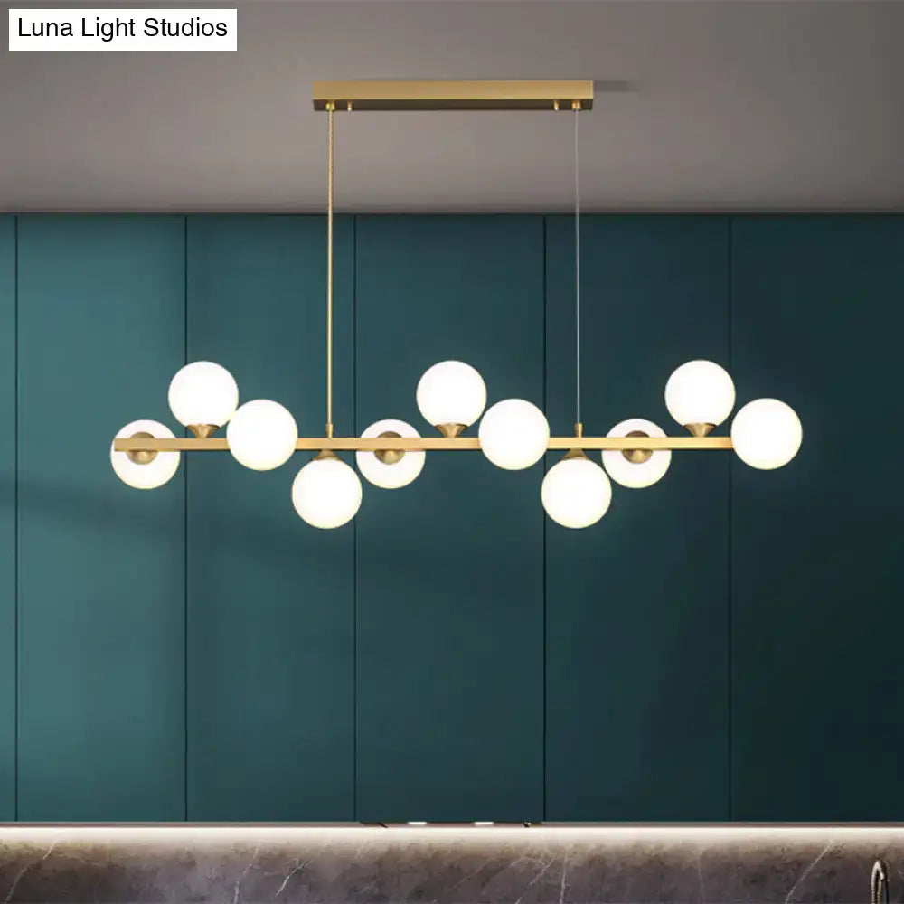 Modern gold-toned decorbites™ orb pendant light with multiple white glass shade globes in an asymmetrical design